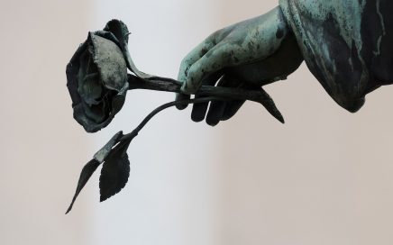 Black and white image of statue holding a rose to illustrate funeral